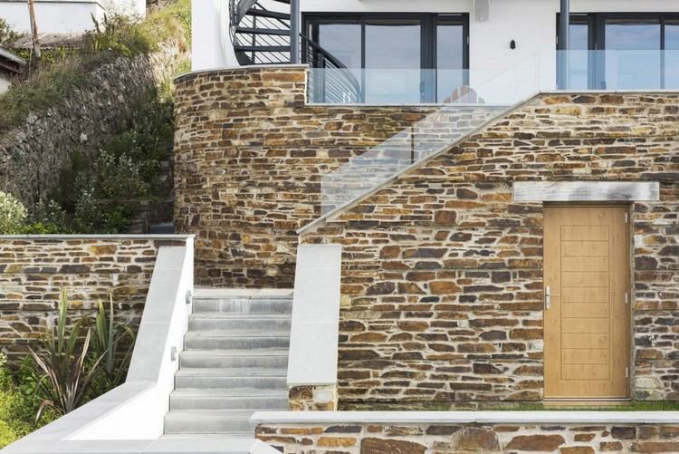Corrimão de vidro - casa - declive - paredes de contenção de pedra - escadas de concreto