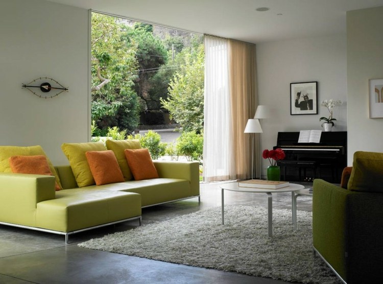Sofá verde de canto da sala de estar com paredes brancas e felpudo tapete