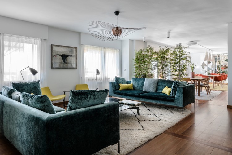 sofá de veludo verde almofadas amarelas poltrona piso de madeira
