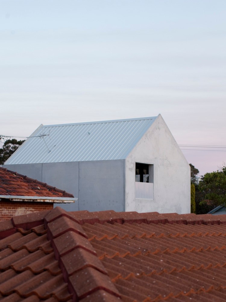 habitação do bairro com telhados vermelhos e casa contrastante com paredes de concreto na cor cinza