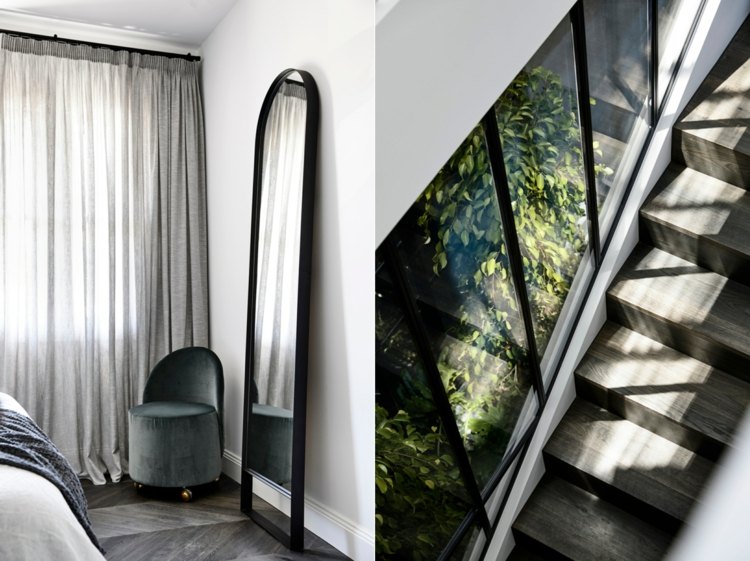 Espelho de pé com moldura de metal preta no quarto e escadas de madeira cinza