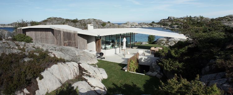 casa com telhado fechado fiorde casa noruega projeto rochas paisagem arredores painéis de madeira concreto vidro vista para o mar gramado