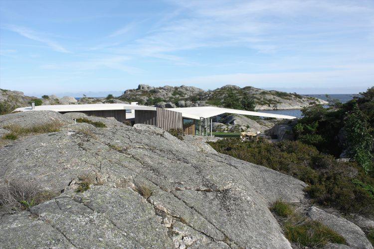 grande vulcão de rocha atrás da casa com telhado inclinado céu luz do dia plantação verde