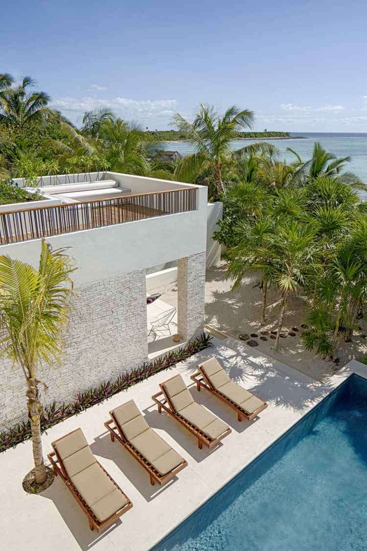 casa com decoração rústica área da piscina espreguiçadeiras terraço com palmeiras