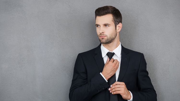 terno preto gravata preta camisa branca combinando parede cinza