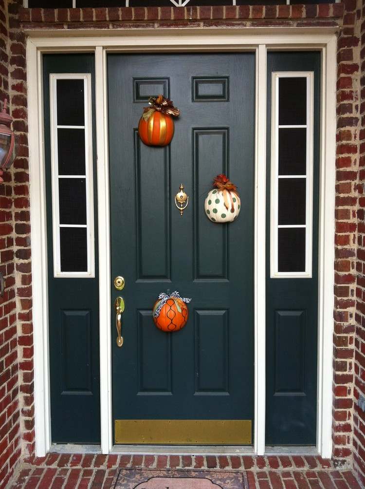 Decoração de outono na frente da entrada da casa cortada pela metade - abóbora - colorida - pintada - pendurada na porta