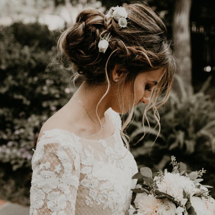 Penteado de noiva com coque frouxamente trançado com flores como acessório de cabelo - penteado no estilo boho