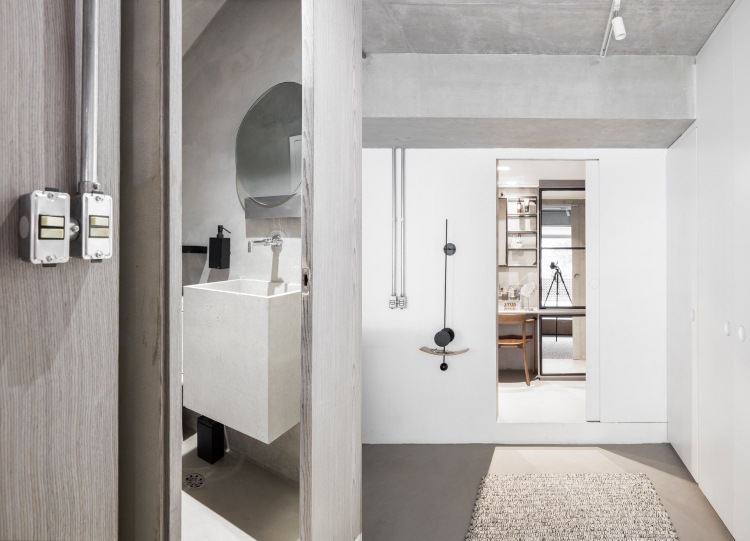 Banheiros brancos e cinza projetam paredes de gesso e pias de piso e concreto