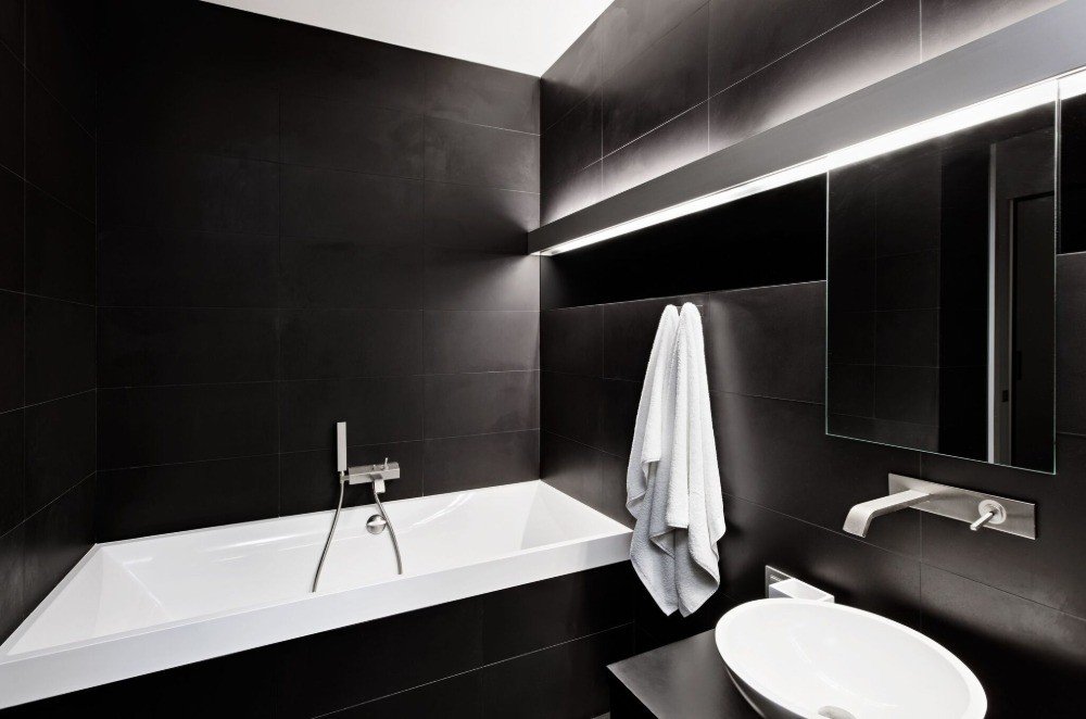 azulejos pretos contrastam com luz branca nos banheiros