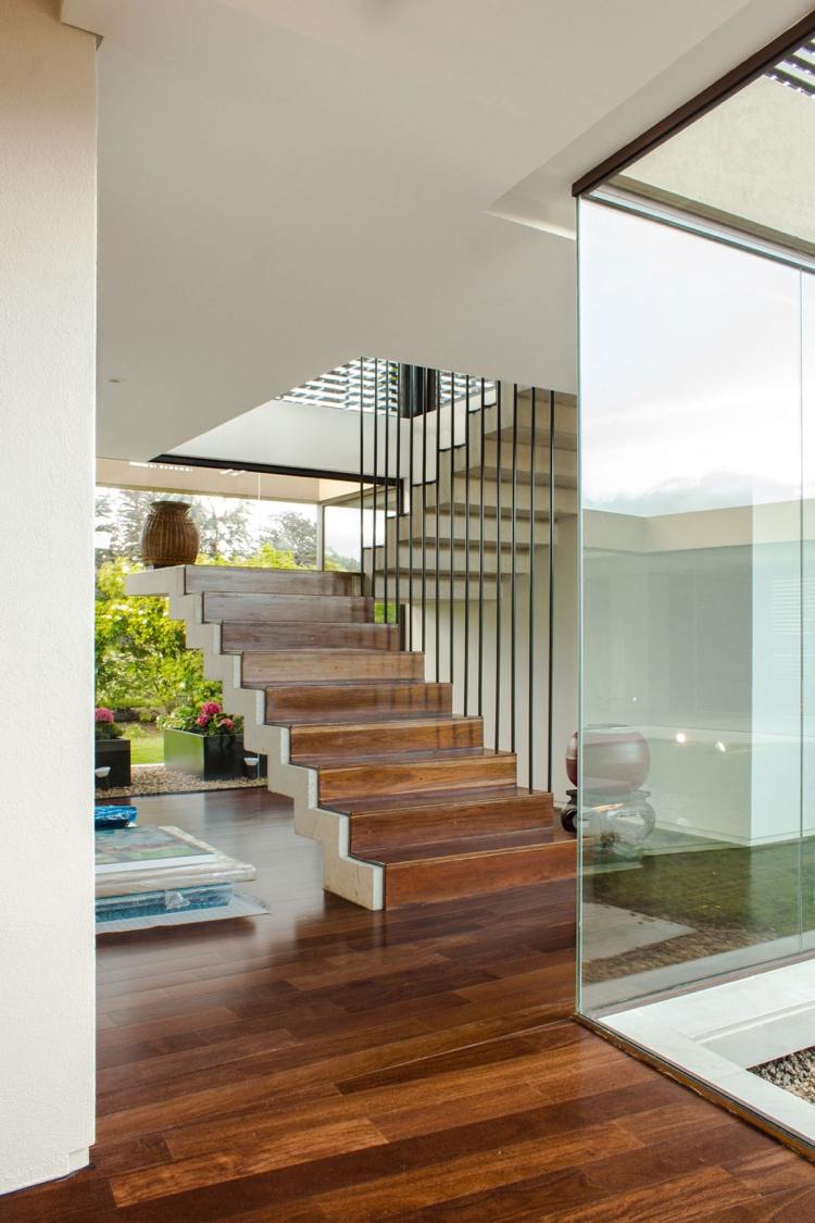 Divisória de vidro - jardim interno - casa luxuosa - piso de parquete - escada escura - andar superior