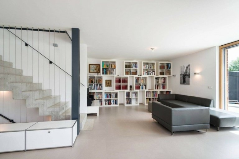 interior feito de madeira e escadas de concreto sofá cinza prateleira de couro branco