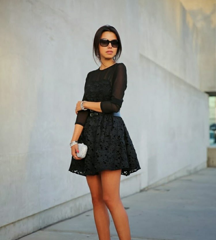 Elegante em preto com vestido de mangas compridas feito de tule e renda e com bolsa de mão