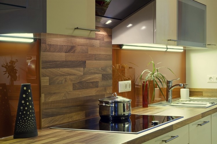 Parede dos fundos da cozinha em madeira, bancada - placa vitrocerâmica - azulejos espelhados - bancada em vidro