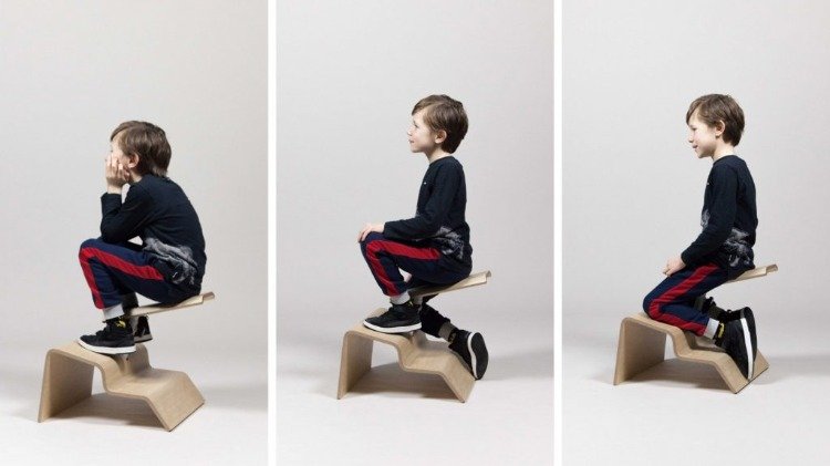aluno muda sua postura sentada em um assento de madeira especialmente projetado