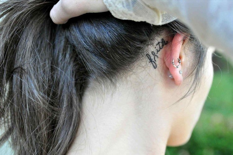 pequenos motivos de tatuagem para mulheres atrás da orelha escrevendo em preto