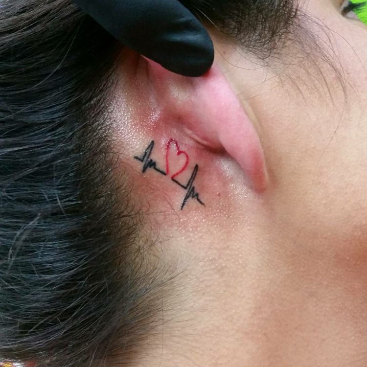 pequena tatuagem com motivos de coração batimento cardíaco mulher preto vermelho atrás da orelha