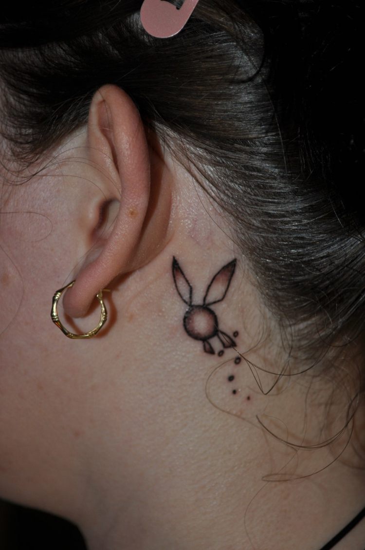 Mulher com motivos abstratos de tatuagem colorida atrás da orelha