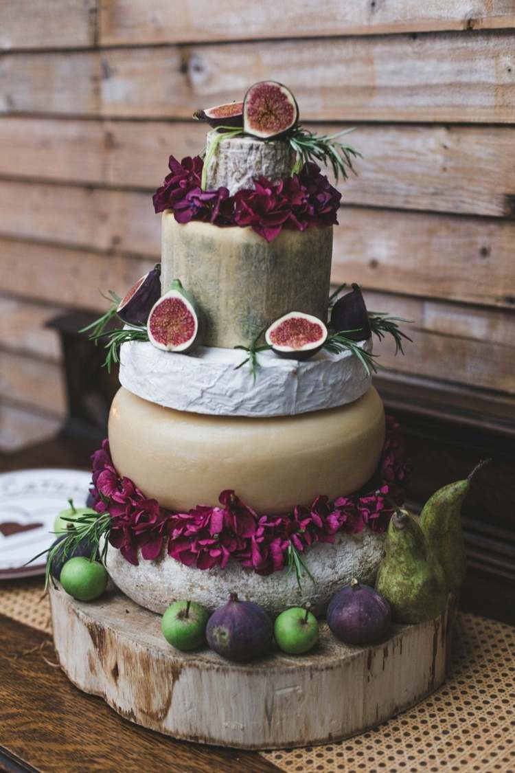 Figos, alecrim e flores roxas para um bolo de queijo rústico em um disco de madeira