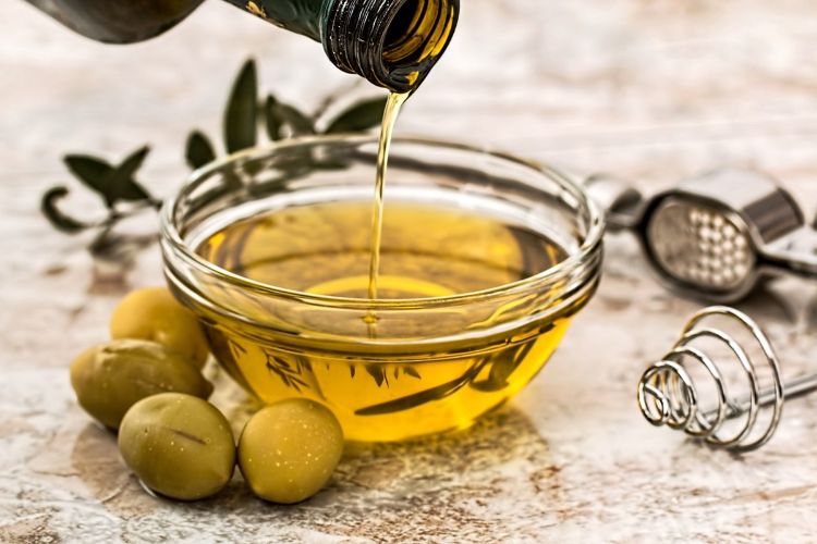 Pegue azeite de oliva para fritar a tigela de vidro da garrafa e despeje as azeitonas nos utensílios de cozinha