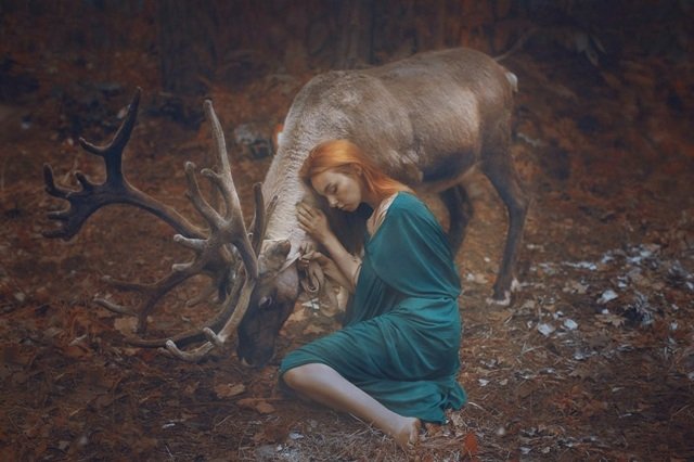 Mulher ruiva com veado na floresta