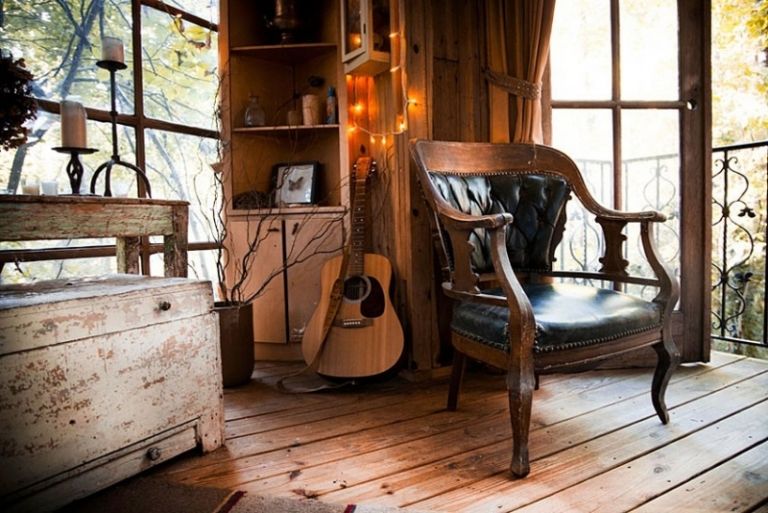 casa na árvore-estar-poltrona-piso de madeira-luzes de fada-violão-cômoda-castiçais