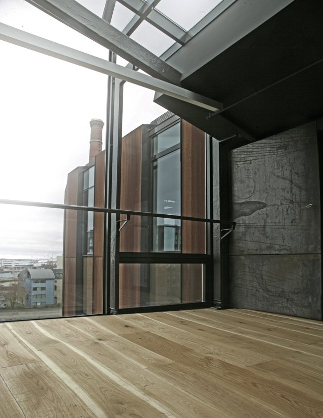 Parede de estilo industrial com fachada de vidro e piso de madeira