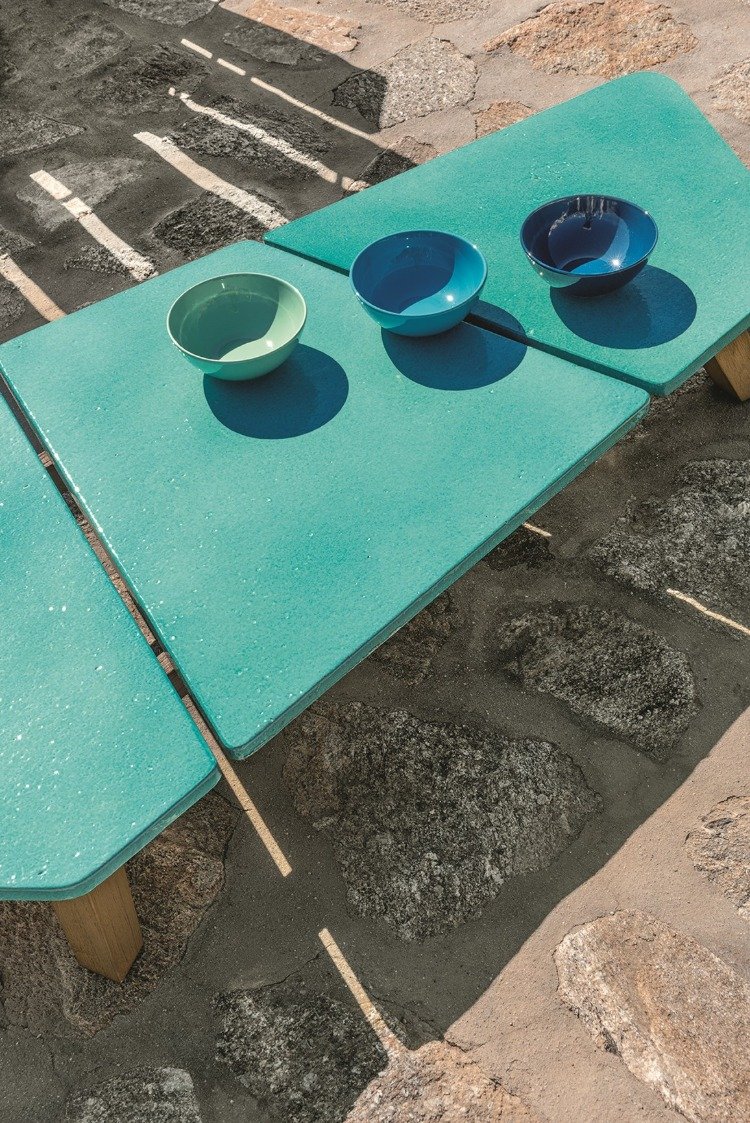 mesa baixa com tampos verdes e formas modernas em piso de pedra