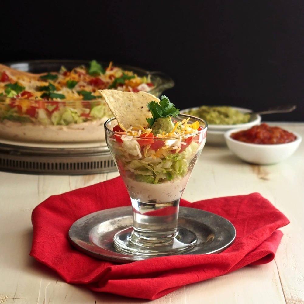 pequena porção de salada mexicana em um copo em prato decorado com pedaços de tortilha