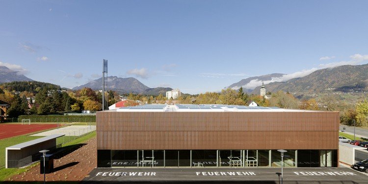 painéis solares colocados no telhado, campo de jogo com uma camada vermelha e uma vista dos Alpes