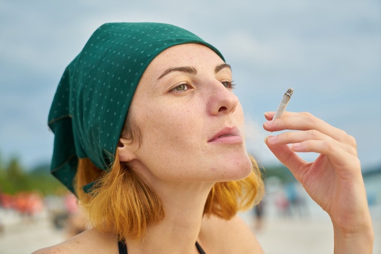 mulher com lenço na cabeça e cigarro de tabaco do lado de fora no verão