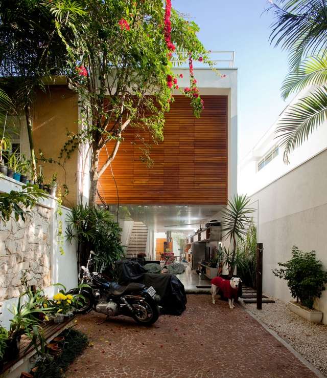 Casa em um lote estreito de entrada de terreno pavimentada com fachada de janelas suspensas de madeira