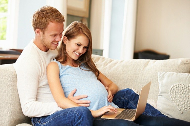 Nomes para gêmeos casal-homem-mulher-grávida-sofá-sala-laptop-almofadas