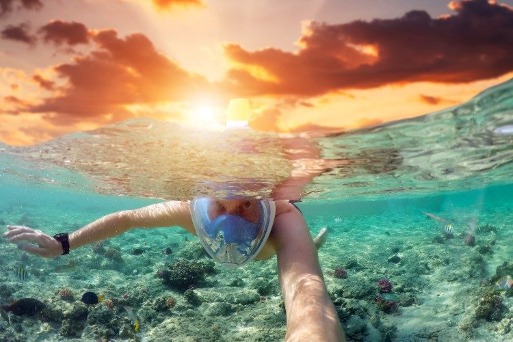 homem com máscara de snorkel enquanto mergulha em uma ilha exótica