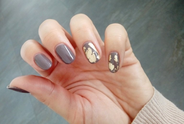 Pintando unhas com idéias de folha de ouro em um fundo cinza