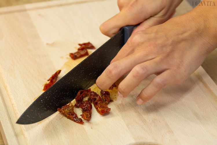 Faca de cozinha pique tomates secos ao sol em pedaços