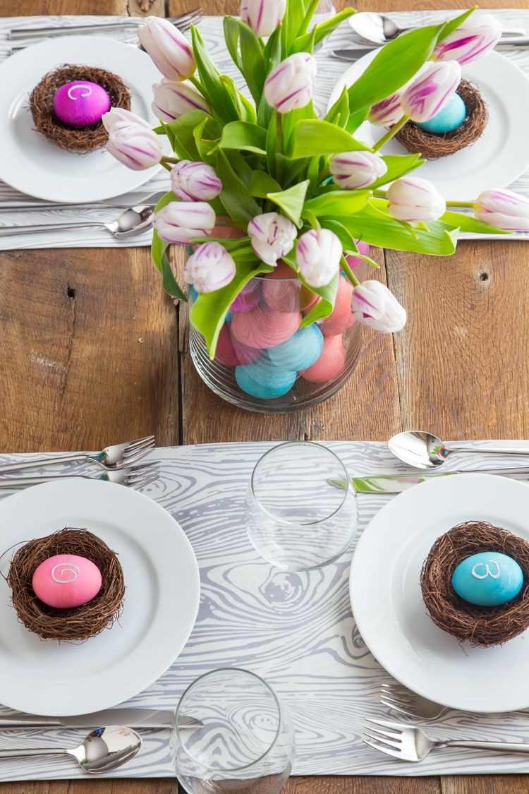 Idéias para decoração de Páscoa com um ninho de pássaro caseiro e tulipas em um vaso com ovos de Páscoa coloridos
