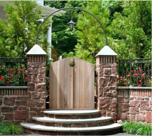 Porta do jardim de madeira, parede de pedra, arco de metal