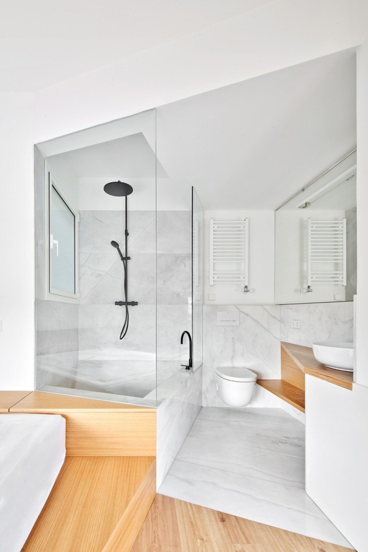 banheiro pequeno revestido em mármore e madeira com divisória de vidro