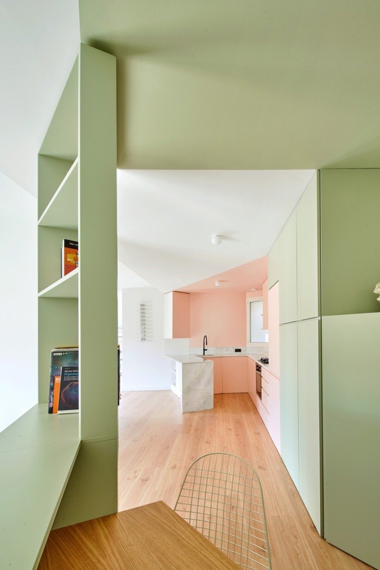 cozinha aberta ao lado de um pequeno escritório com prateleiras verde-menta
