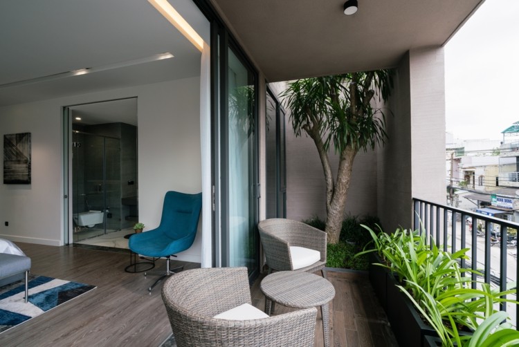 Terraço do quarto com janelas do chão ao teto plantando poltronas de vime