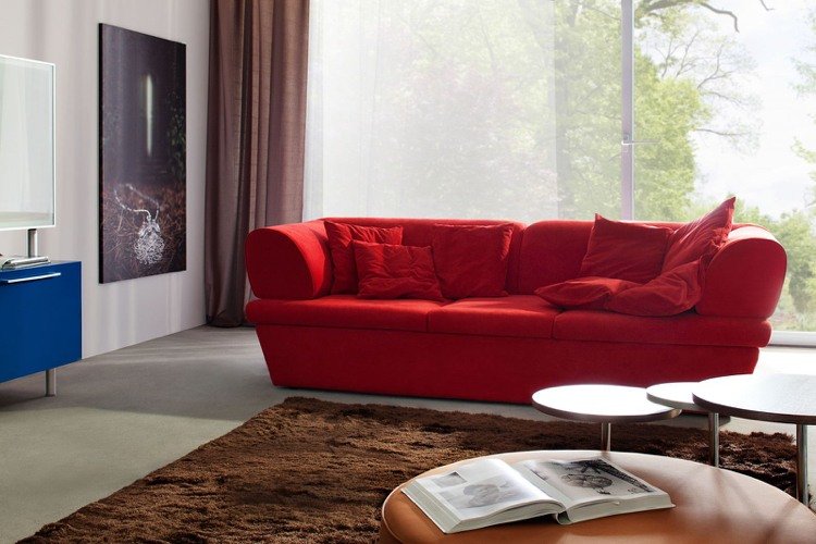 sofá vermelho, carpete marrom, cortinas, piso de concreto