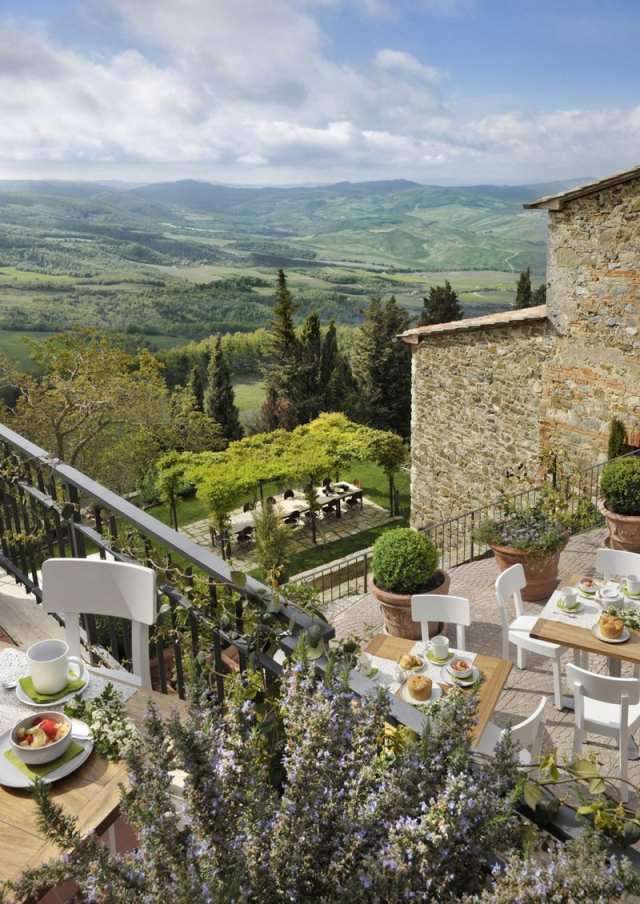 Hotel toscano com vista para o terraço entre campos de vinho e grades de metal Monteverdi