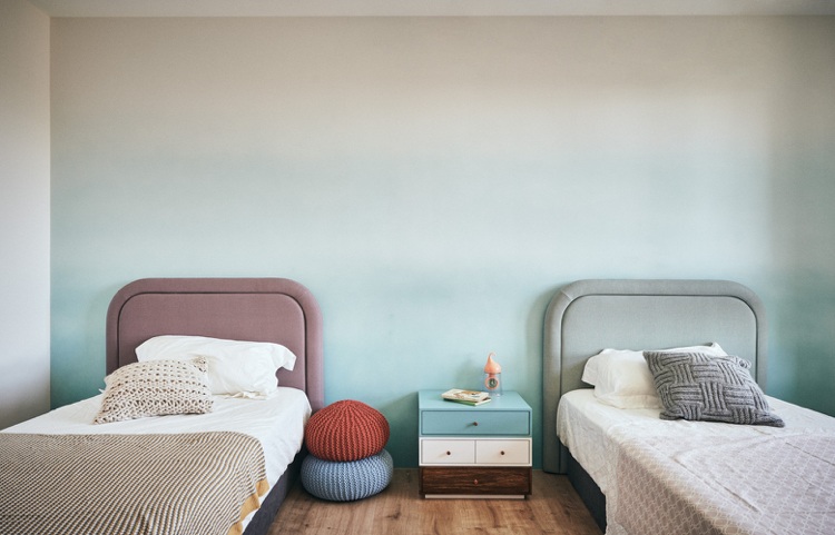 mesa de cabeceira azul com parede ombre com duas camas
