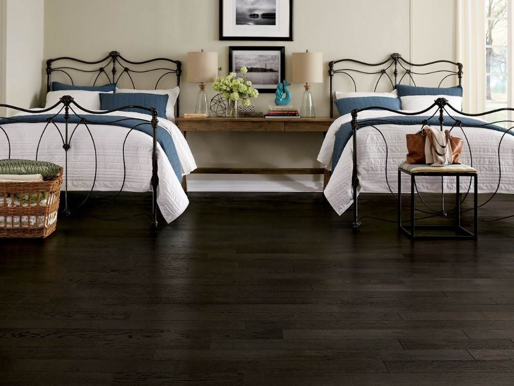 quarto duplo com piso laminado preto na frente de duas camas de estilo retro