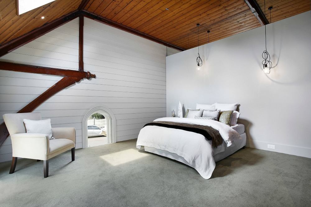 quarto com teto de madeira e piso acarpetado com poltrona e lâmpada suspensa de cama de casal e paredes brancas