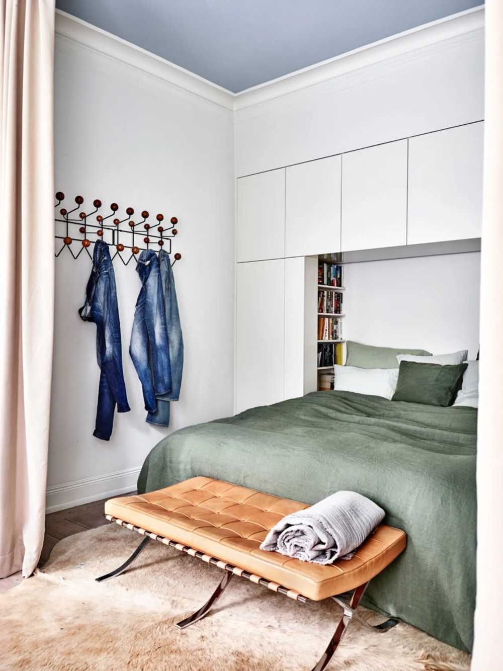 piso claro do quarto com couro bovino e pufe com couro ao lado das capas de edredom verdes