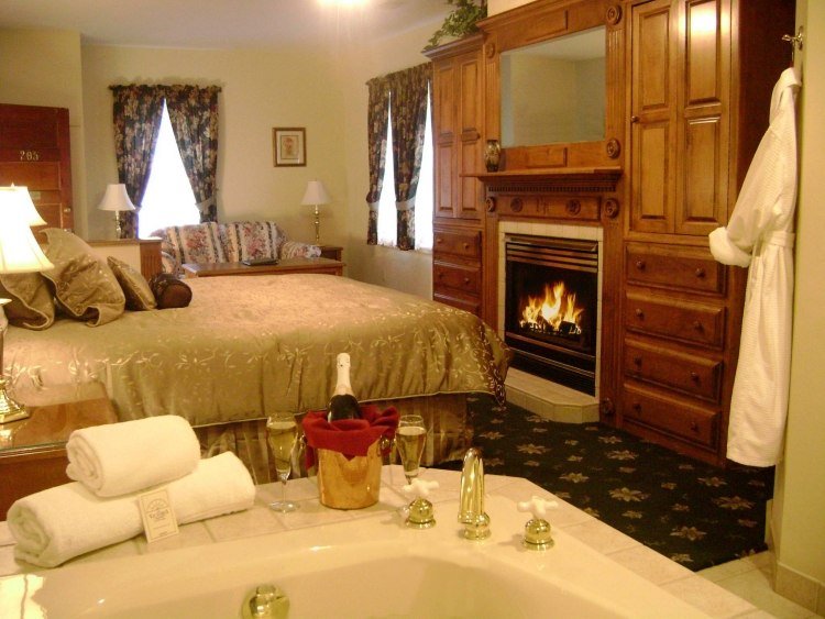 quarto-hidromassagem-cama-lareira-parede de madeira-luxo-colcha-ouro-vinho espumante-quarto de hotel-romântico