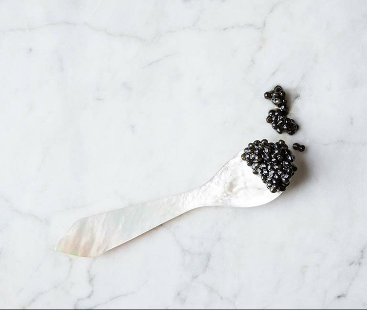 Caviar preto servindo talheres de colher de prata com entradas gastronômicas