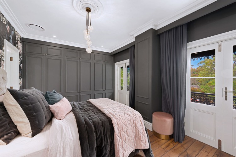 Quarto com decoração chique surrada e cama de parede de madeira cinza colcha rosa