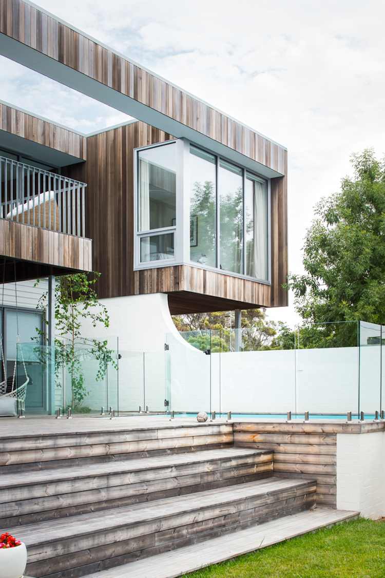 terraço de madeira térmica com fachada de madeira envelhecida cobrindo a parede de vidro da piscina